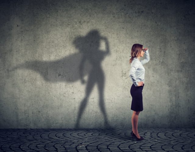 Side view of a business woman imagining to be a super hero looking aspired.